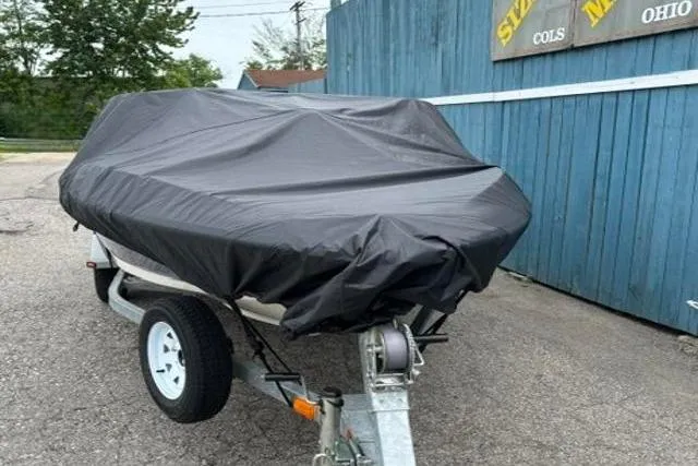 Slide: The Image of Covered 2010 Bayliner 175 Bowrider on trailer, parked beside blue wooden fence. - 23