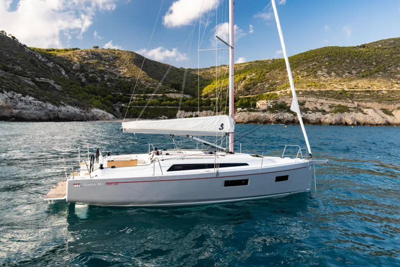 Slide: The Image of Beneteau Oceanis 34.1 sailboat 2026 on calm waters near coastal landscape. - 10