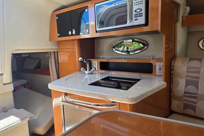 Slide: The Image of 2007 Chaparral Signature 250 boat interior with kitchenette, featuring sink, stove, and microwave. - 12