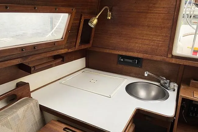 Slide: The Image of 1995 Com-Pac 25 sailboat interior with wooden cabinetry and compact kitchen area. - 12