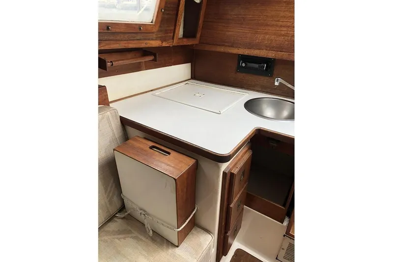 Slide: The Image of Interior of 1995 Com-Pac 25 sailboat featuring compact kitchen area with sink and storage. - 13