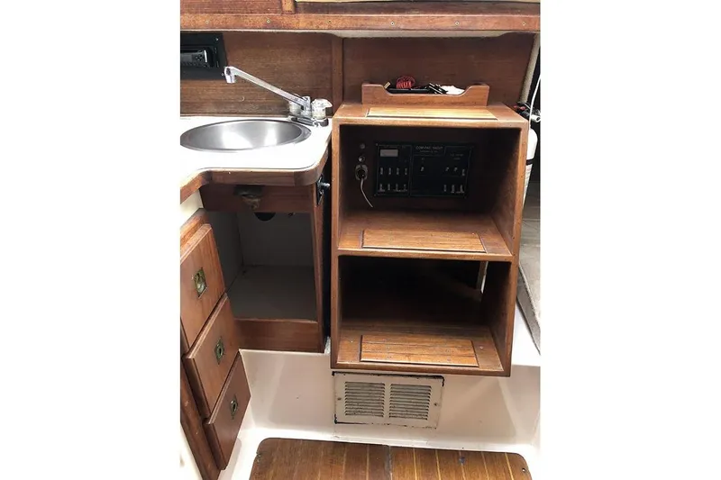 Slide: The Image of 1995 Com-Pac 25 sailboat interior with sink, wooden cabinetry, and control panel. - 14