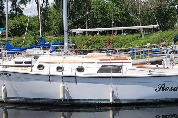 Slide: The Image of 1995 Com-Pac 25 sailboat docked, featuring white hull and visible rigging. - 4