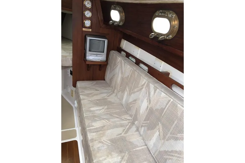 Slide: The Image of Interior of 1995 Com-Pac 25 sailboat with cushioned seating and portholes. - 5