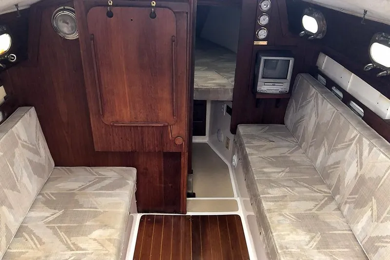 Slide: The Image of Interior of a 1995 Com-Pac 25 sailboat with cushioned seating and wooden accents. - 6
