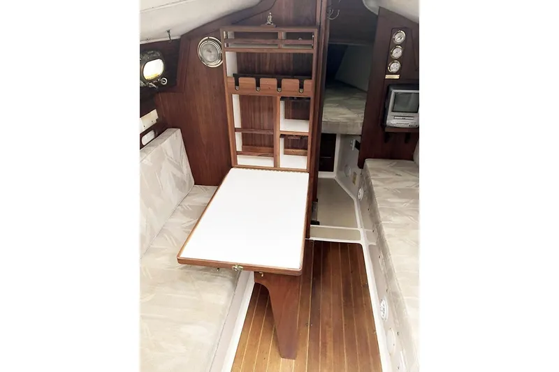 Slide: The Image of Interior of a 1995 Com-Pac 25 sailboat featuring a compact dining area and wooden cabinetry. - 8