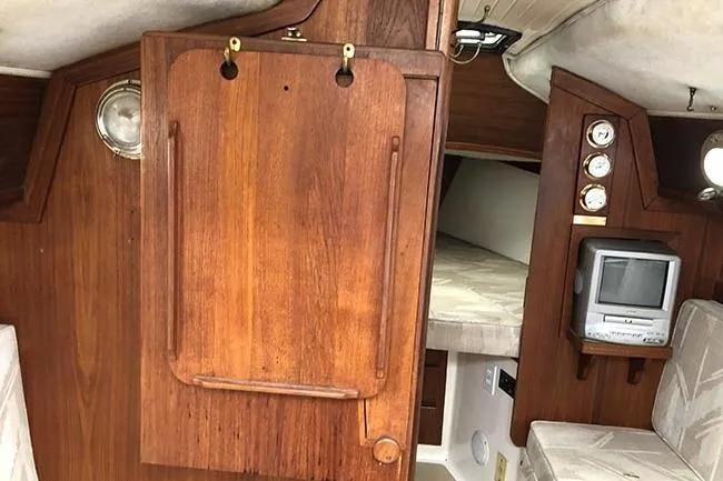 Slide: The Image of Interior of a 1995 Com-Pac 25 sailboat with wood paneling and compact amenities. - 9