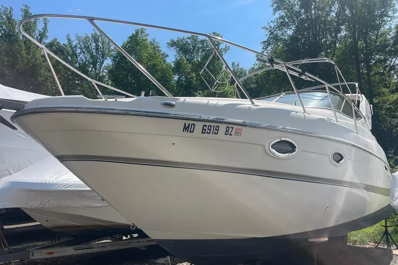 The Image of 2002 Maxum 2700 SCR boat on trailer, surrounded by trees. - 0