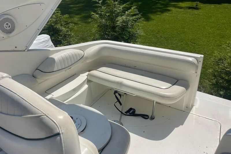 Slide: The Image of 2002 Maxum 2700 SCR boat interior with white seating and lush green background. - 6