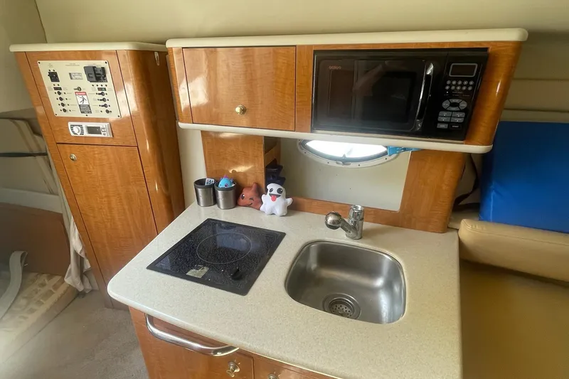 Slide: The Image of 2002 Maxum 2700 SCR boat kitchenette with sink, stove, and microwave. - 9