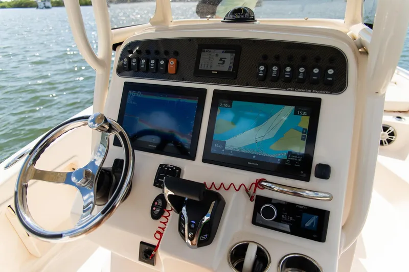 Slide: The Image of 2024 Grady-White 231 Coastal Explorer boat dashboard with navigation screens and controls. - 18
