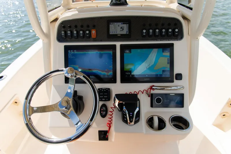 Slide: The Image of 2024 Grady-White 231 Coastal Explorer boat dashboard with navigation screens and steering wheel. - 19
