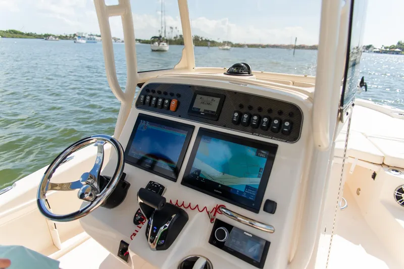 Slide: The Image of 2024 Grady-White 231 Coastal Explorer boat dashboard with navigation screens and steering wheel. - 20