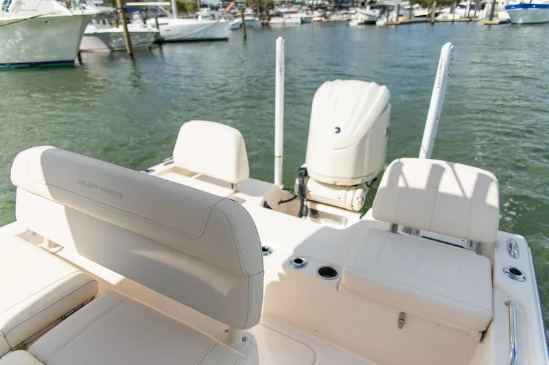 Slide: The Image of 2024 Grady-White 231 Coastal Explorer boat interior with seating and motor, docked in marina. - 24