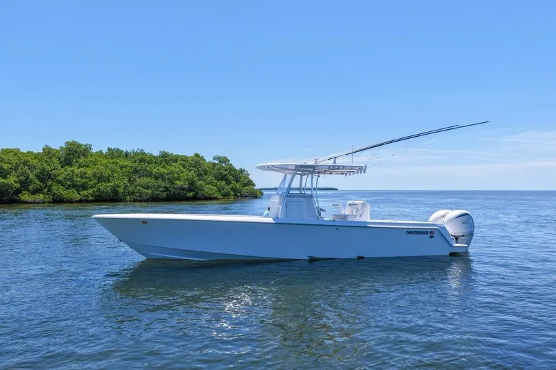 The Image of 2025 Contender 32 ST boat on calm water near lush green island. - 1