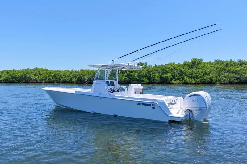 Slide: The Image of 2025 Contender 32 ST boat on water, clear sky, lush green shoreline. - 11