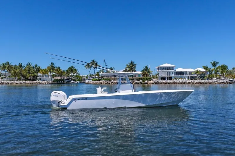 Slide: The Image of 2025 Contender 32 ST boat cruising on a sunny day near waterfront homes. - 2
