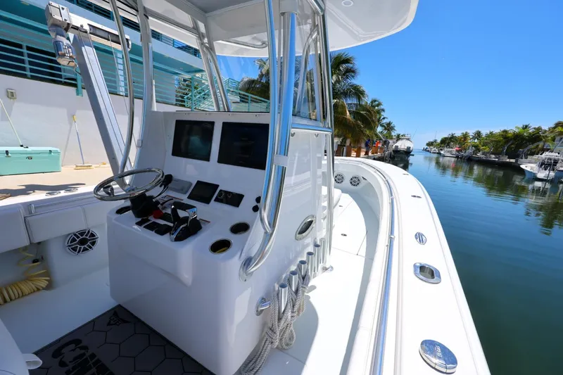 Slide: The Image of 2025 Contender 32 ST boat helm with dual screens, docked by a scenic canal. - 23