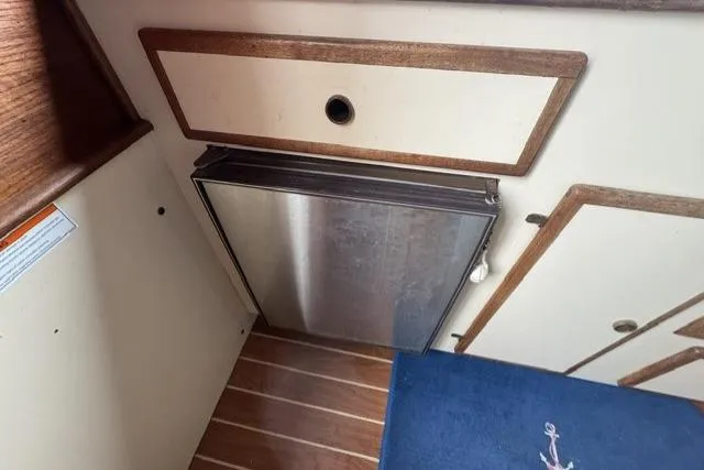 Slide: The Image of Interior of a 1983 Nordic Tug 26, featuring a compact stainless steel fridge. - 12