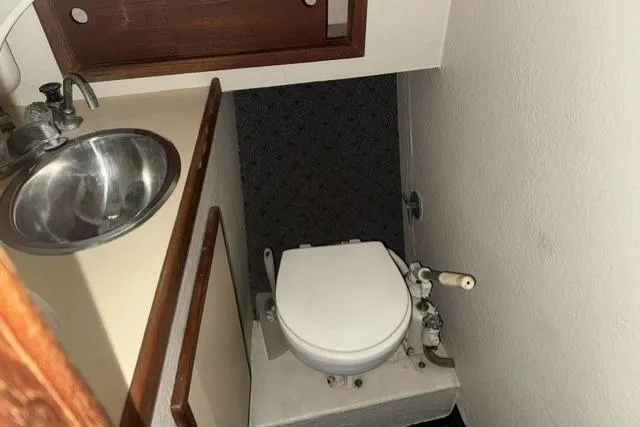 Slide: The Image of Compact bathroom in a 1983 Nordic Tug 26, featuring a sink and marine toilet. - 14