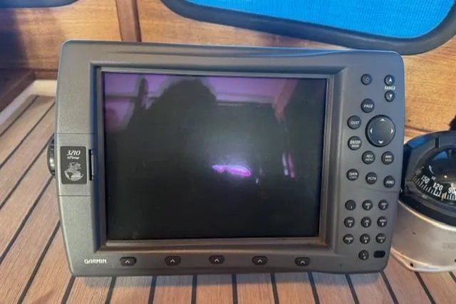 Slide: The Image of Garmin GPS device on 1983 Nordic Tug 26 boat, displayed on wooden surface. - 17