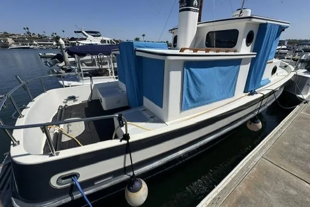 Slide: The Image of 1983 Nordic Tug 26 docked at marina, featuring blue accents and classic design. - 2