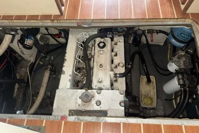 Slide: The Image of Engine compartment of a 1983 Nordic Tug 26, showcasing mechanical components and hoses. - 24