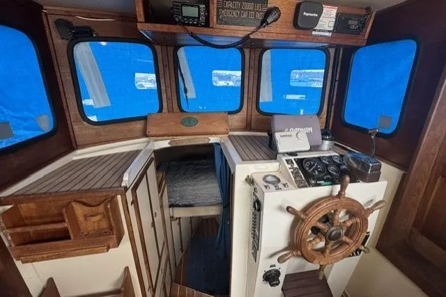 Slide: The Image of 1983 Nordic Tug 26 interior with wooden helm, navigation equipment, and blue window covers. - 5