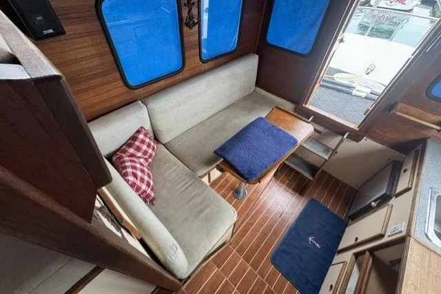 Slide: The Image of Cozy interior of a 1983 Nordic Tug 26 with wooden flooring and blue accents. - 6