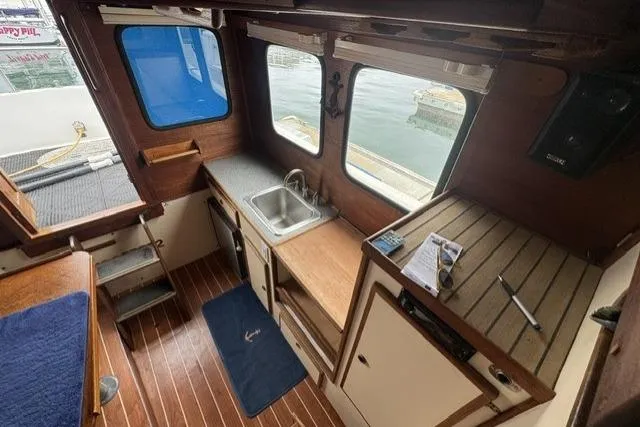 Slide: The Image of Interior of 1983 Nordic Tug 26 with wooden flooring and compact kitchen area. - 8