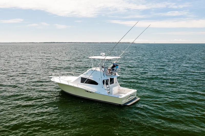 Slide: The Image of 1994 Luhrs 38 Convertible boat on open water, clear sky, fishing rods visible. - 13