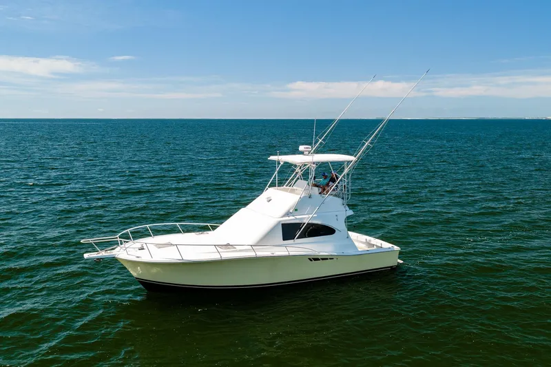 Slide: The Image of 1994 Luhrs 38 Convertible yacht cruising on open water under clear blue skies. - 17