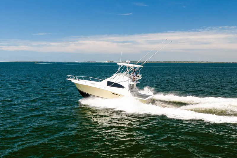 Slide: The Image of 1994 Luhrs 38 Convertible yacht cruising on open water under clear blue skies. - 21