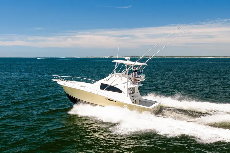Slide: The Image of 1994 Luhrs 38 Convertible yacht cruising on open water under clear skies. - 23