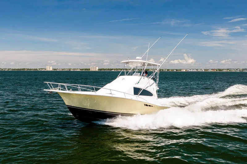 Slide: The Image of 1994 Luhrs 38 Convertible yacht cruising on open water under clear blue skies. - 24