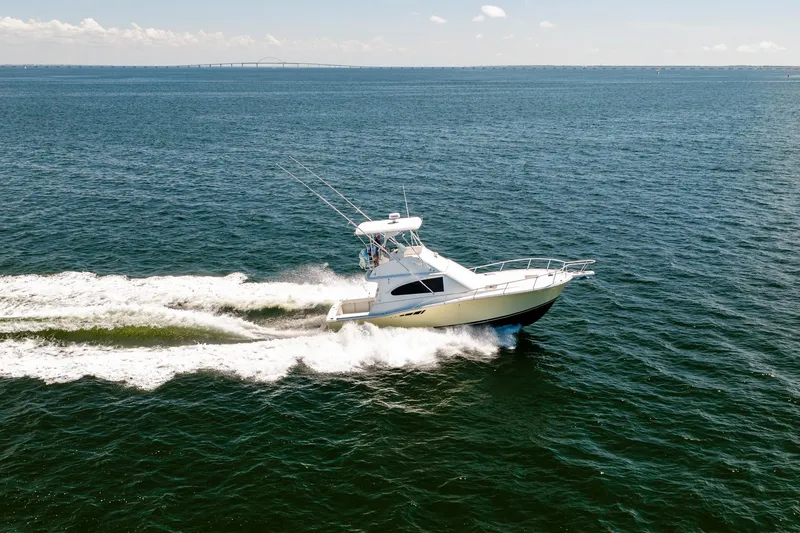 Slide: The Image of 1994 Luhrs 38 Convertible yacht cruising on open water under clear skies. - 27