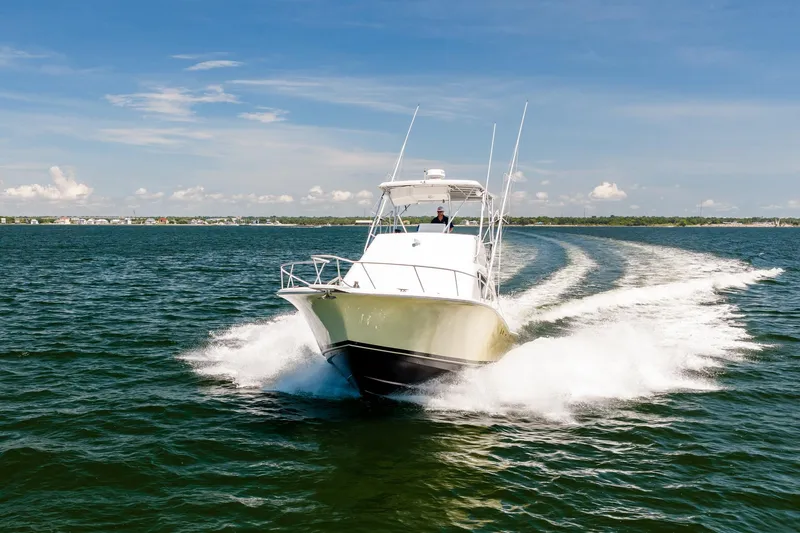 Slide: The Image of 1994 Luhrs 38 Convertible yacht cruising on open water under clear blue skies. - 3