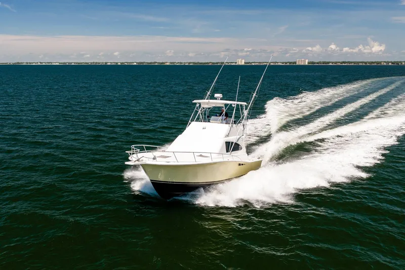 Slide: The Image of 1994 Luhrs 38 Convertible yacht cruising on open water under clear skies. - 34