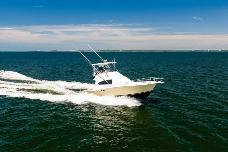Slide: The Image of 1994 Luhrs 38 Convertible yacht cruising on open water under clear blue skies. - 38