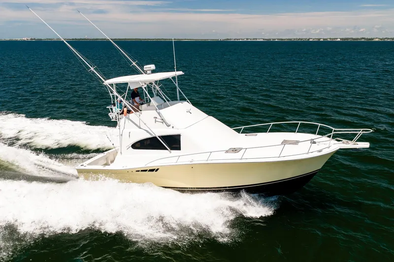 Slide: The Image of 1994 Luhrs 38 Convertible yacht cruising on open water, clear sky background. - 40