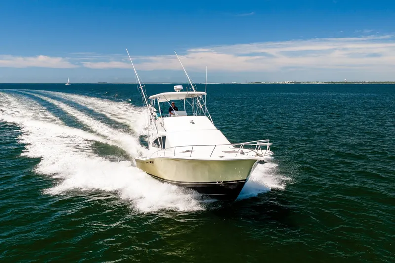 Slide: The Image of 1994 Luhrs 38 Convertible yacht cruising on open water under clear blue skies. - 41