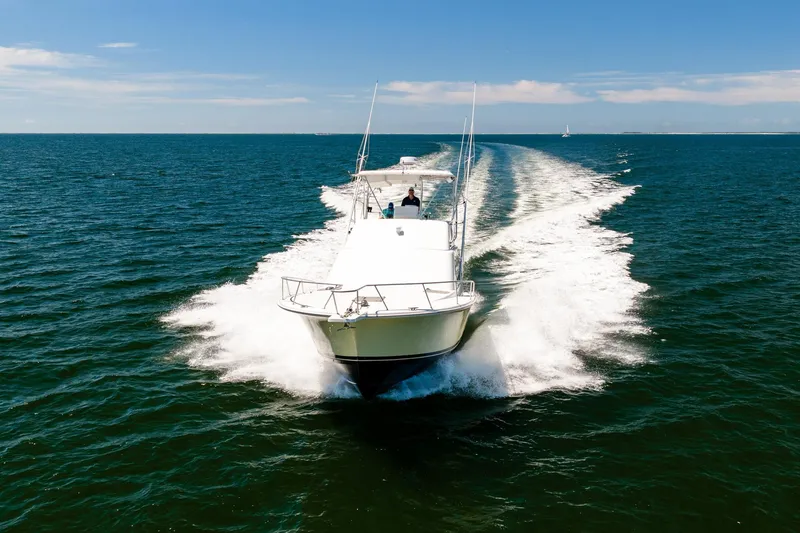 Slide: The Image of 1994 Luhrs 38 Convertible yacht cruising on open water under clear skies. - 44