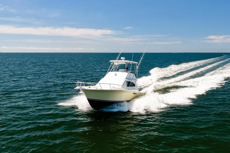Slide: The Image of 1994 Luhrs 38 Convertible yacht cruising on open sea under clear blue sky. - 46