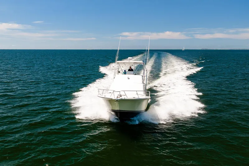 Slide: The Image of 1994 Luhrs 38 Convertible yacht cruising on open water under clear blue skies. - 47