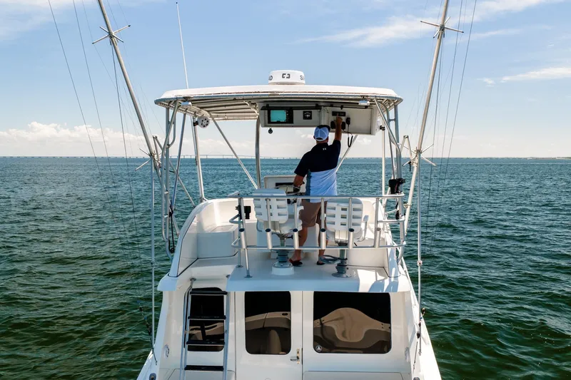 Slide: The Image of 1994 Luhrs 38 Convertible yacht cruising on open water, with a person at the helm. - 54