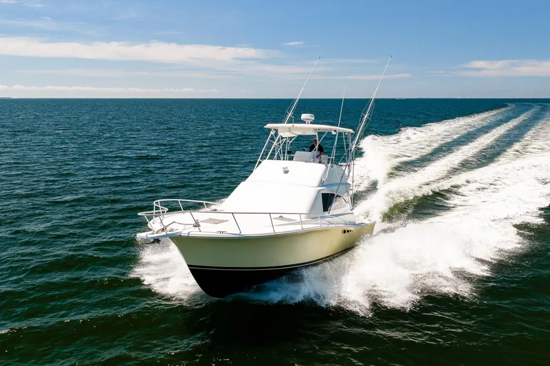 Slide: The Image of 1994 Luhrs 38 Convertible yacht cruising on open water, creating a dynamic wake. - 61