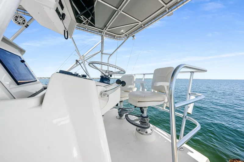 Slide: The Image of 1994 Luhrs 38 Convertible boat helm with ocean view, featuring steering wheel and seating. - 62