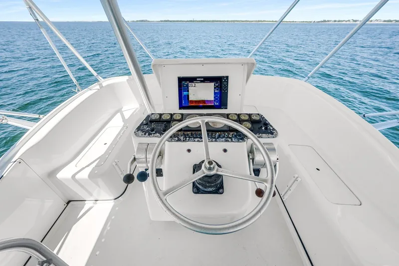 Slide: The Image of 1994 Luhrs 38 Convertible boat helm with steering wheel and navigation display on open water. - 64