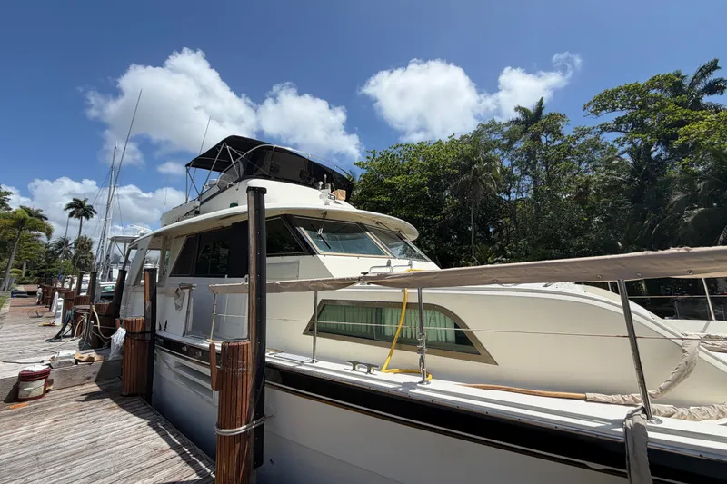 Slide: The Image of 1978 Hatteras 53 Motor Yacht docked under a clear blue sky with lush greenery. - 2