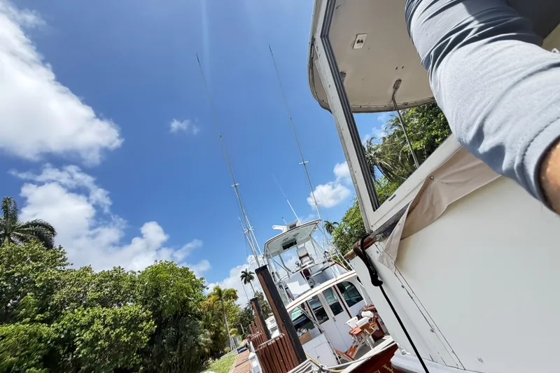 Slide: The Image of 1978 Hatteras 53 Motor Yacht docked under a clear blue sky with lush greenery. - 30